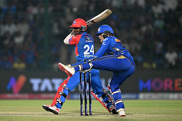 Delhi Capitals' Abishek Porel (L) plays a shot as Mumbai Indians' wicketkeeper Ryan Rickelton reacts during the Indian Premier League (IPL) Twenty20 cricket match between Delhi Capitals and Mumbai Indians at the Arun Jaitley